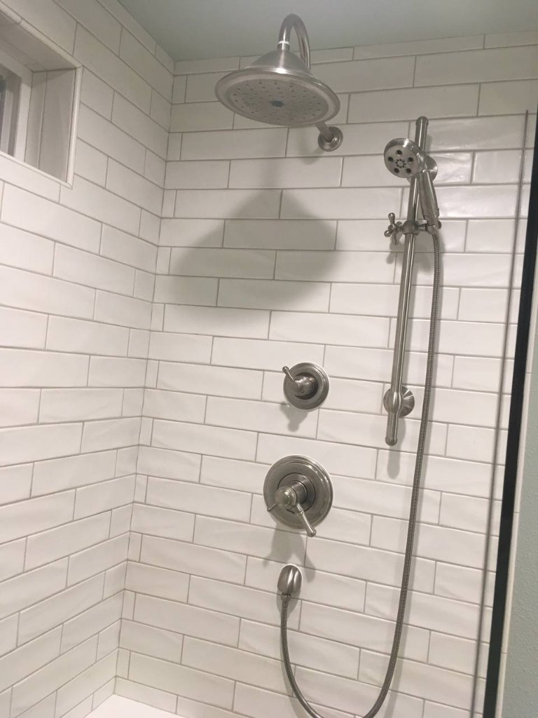 Frameless glass shower — large subway tile, pebble floor, built-in niche, brushed nickel