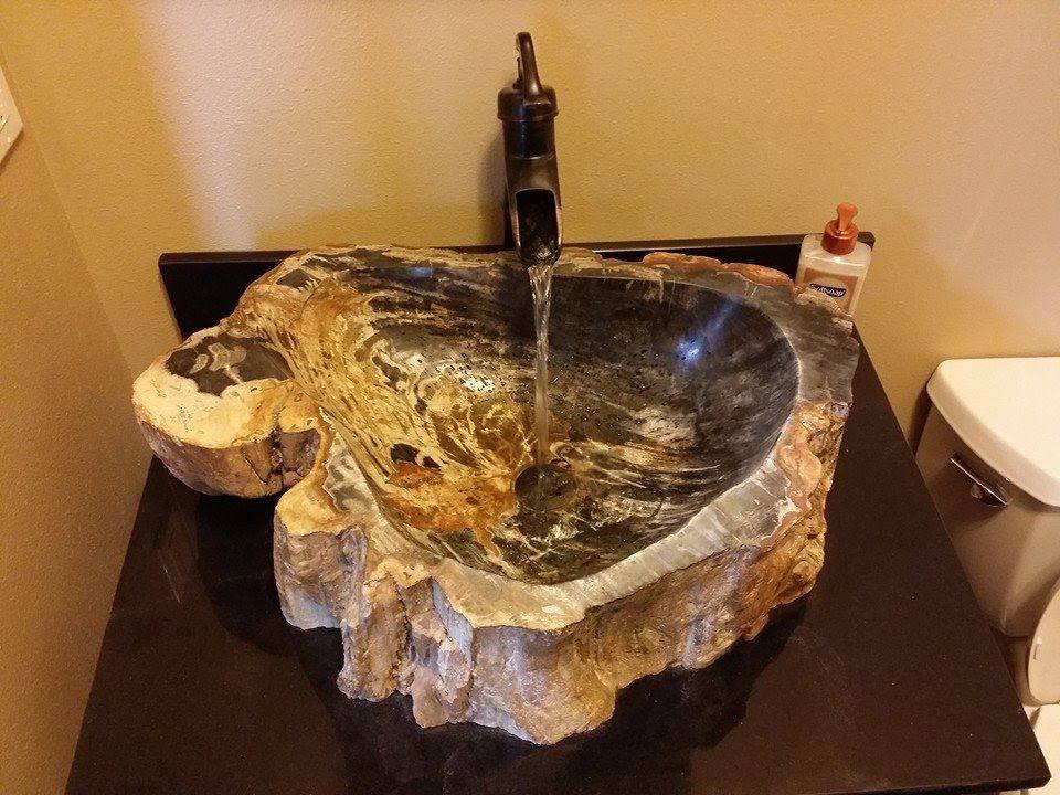 Petrified wood vessel sink sourced from a local Bellingham artist — ancient geology as functional art — mounted on custom antique dresser base