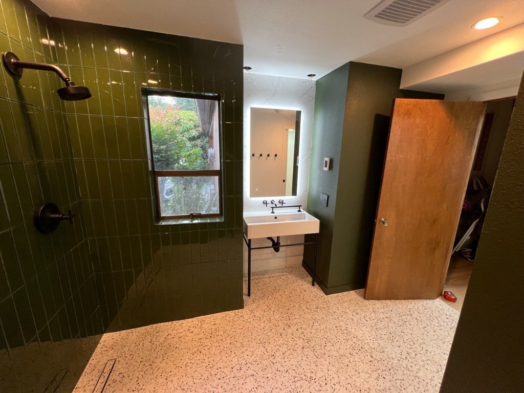 Double shower close — matte black rain heads, linear drain, terrazzo