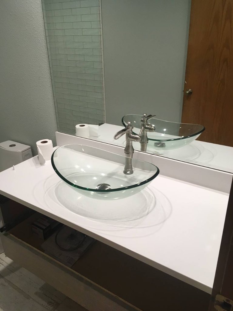Clear glass vessel sink on white quartz — bamboo style brushed nickel faucet