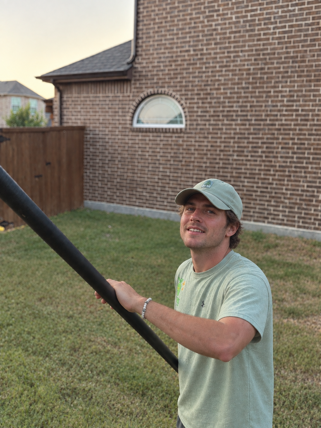 Kiwi technician smiling while cleaning windows on a pole