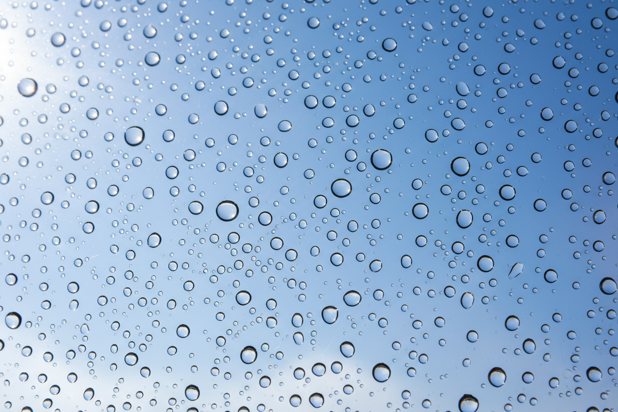 Crystal clear water droplets on treated glass demonstrating pristine window cleaning quality