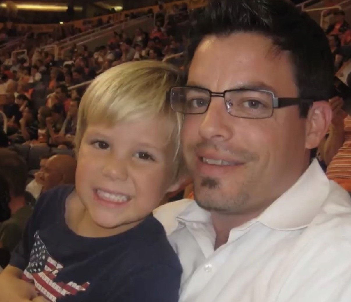 A young Miles Wallace as a child with his father at an arena event, both smiling in the stands.