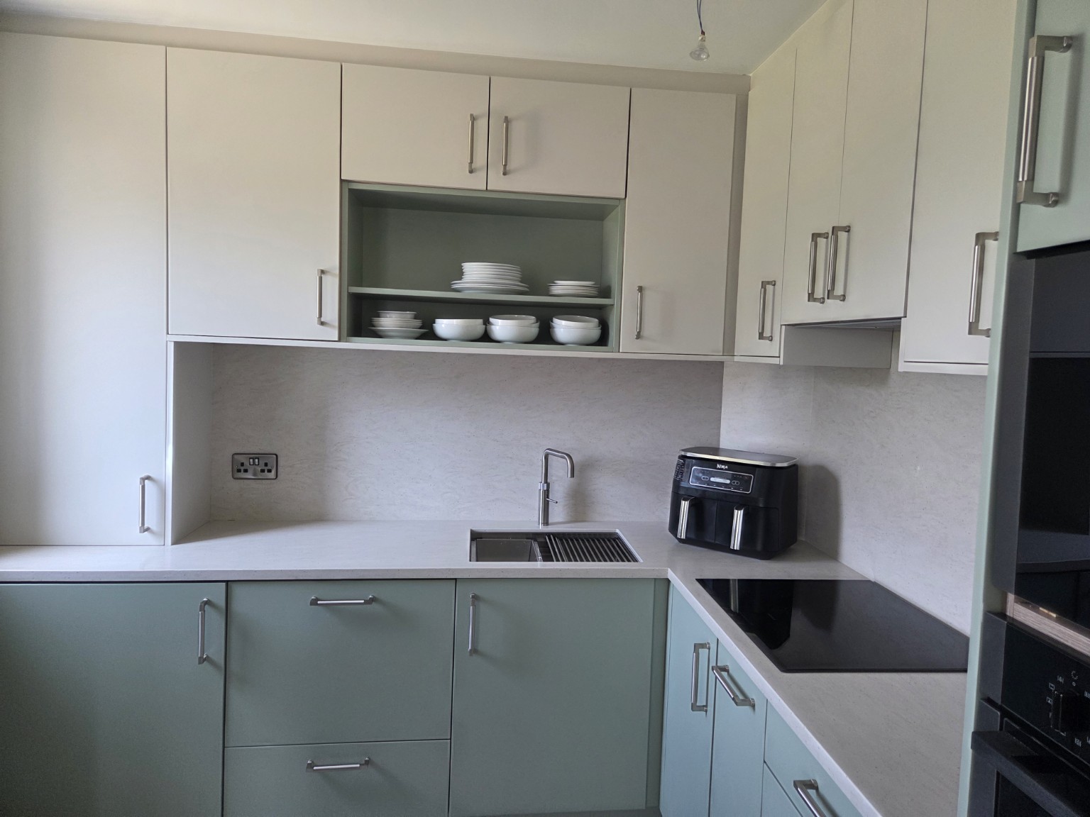 Accessible bespoke kitchen with Bunratty Green base cabinets, Skimming Stone wall units and Hanex Cascade Beige surfaces.