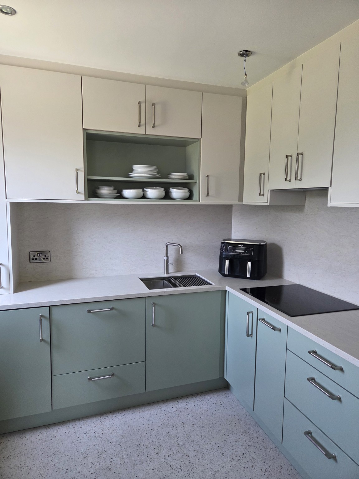 Completed accessible kitchen with easy-grip handles, open crockery shelving, sink and induction hob.