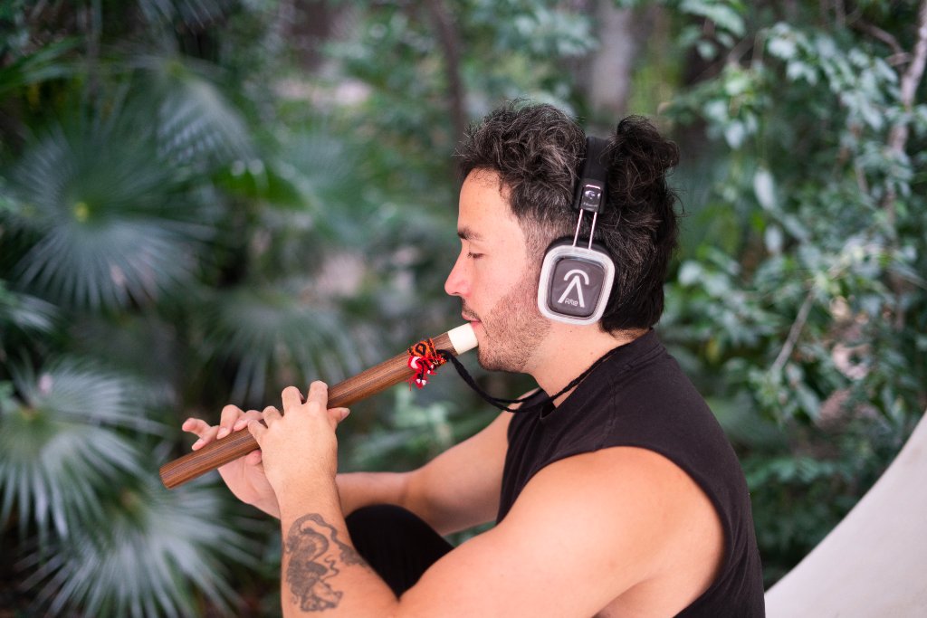 Tribu Halo musician playing flute with immersive headphones in nature