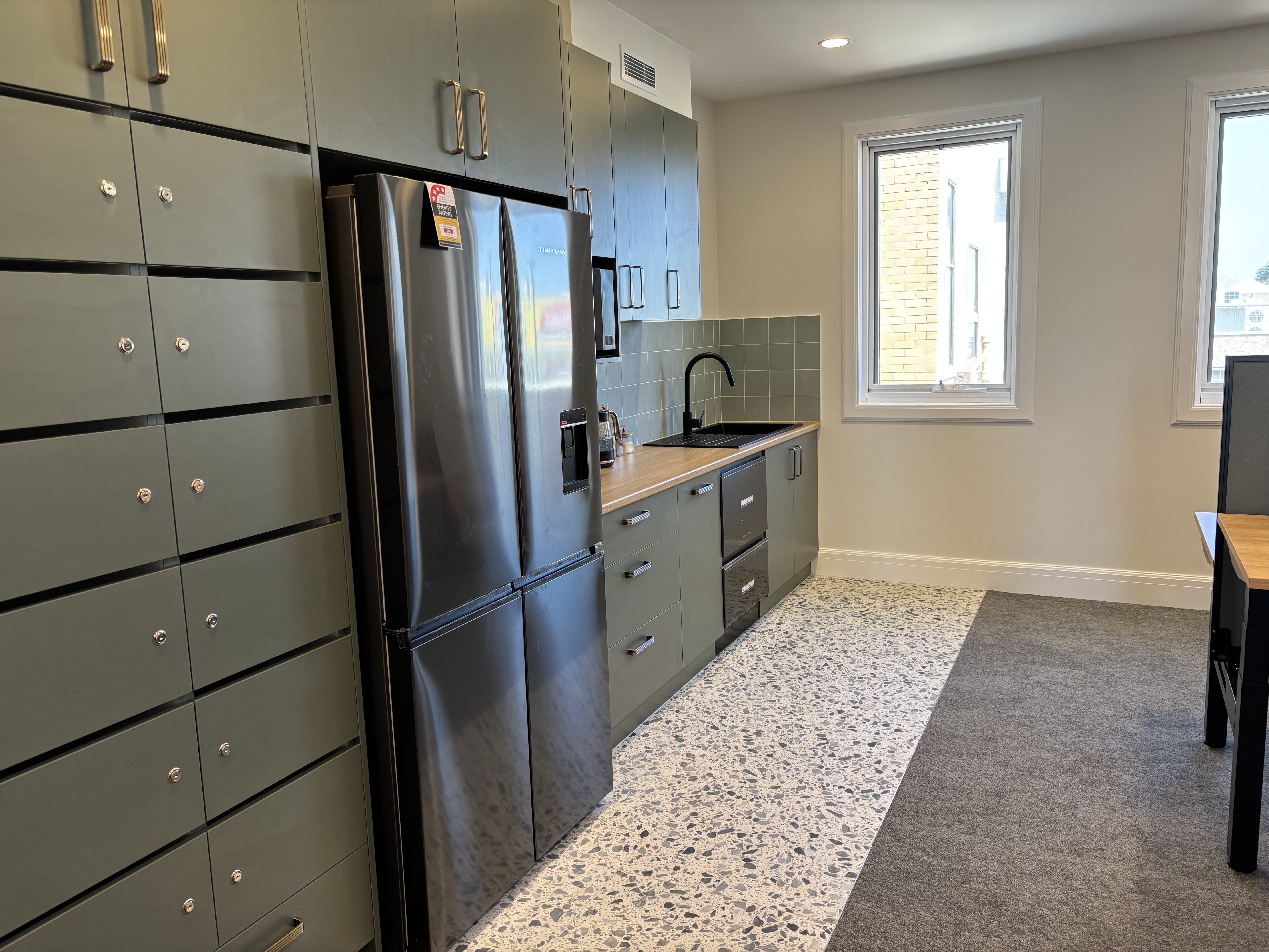 Kitchenette with sage-green cabinetry and oak countertop