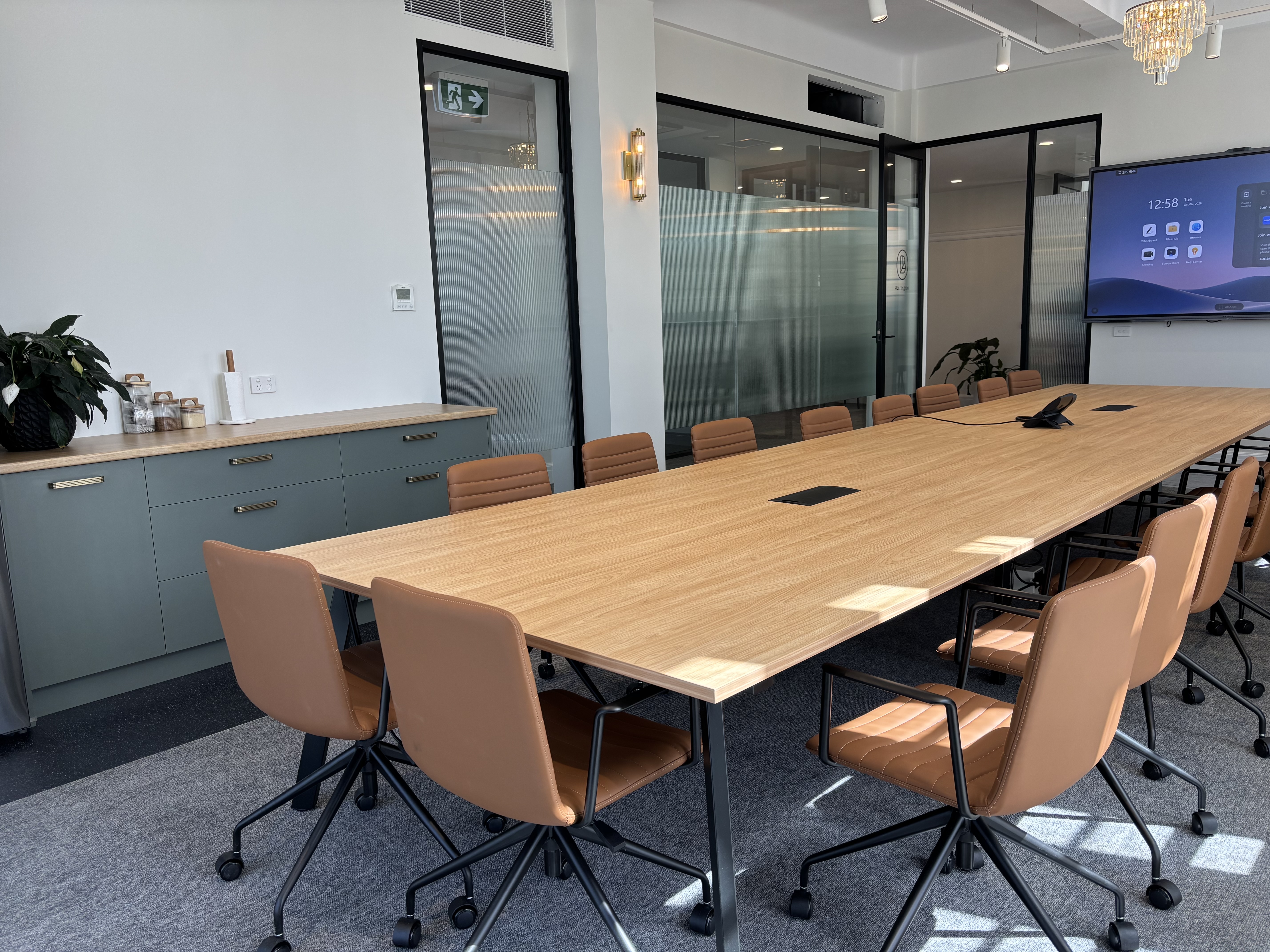 Boardroom with smart display and sage-green cabinetry