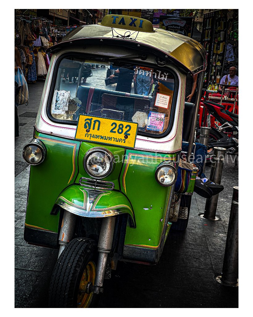 Bright green tuk-tuk taxi parked on a Bangkok street