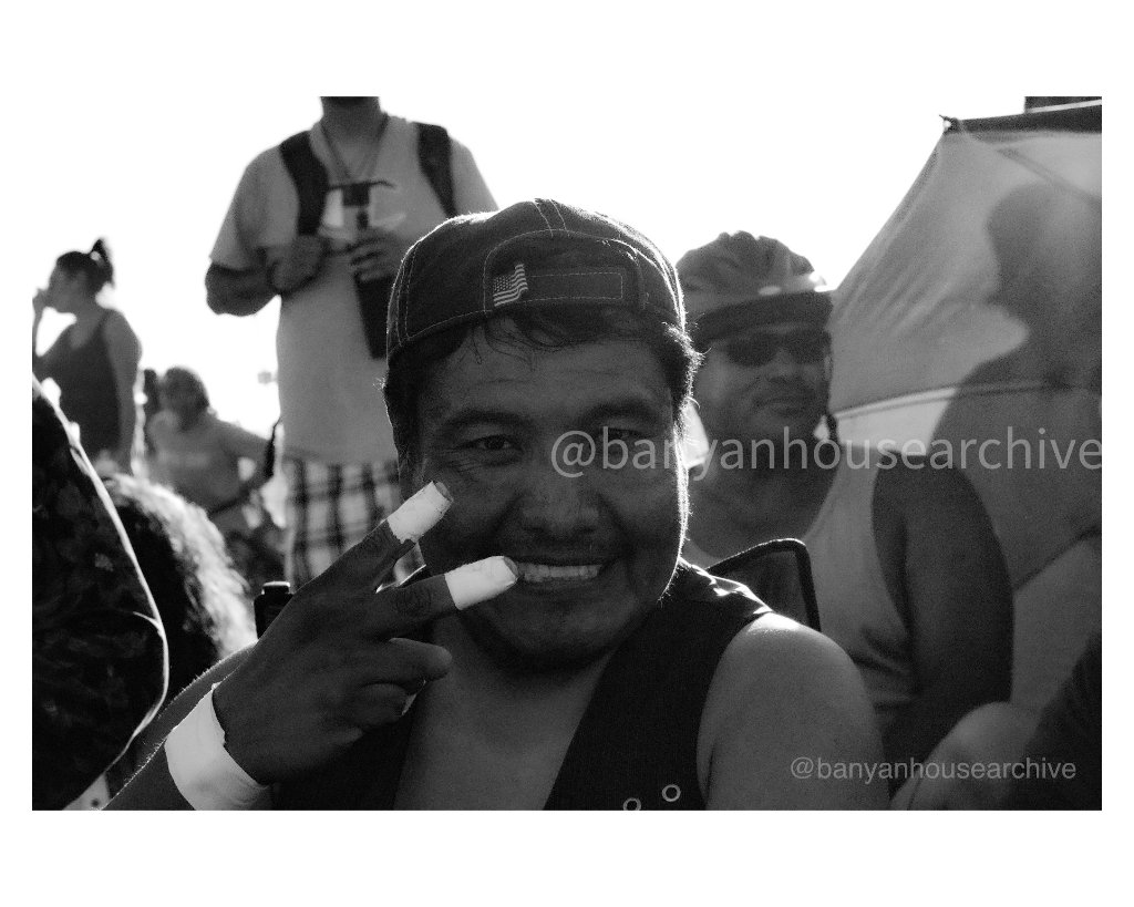 Smiling man flashing a peace sign, black and white