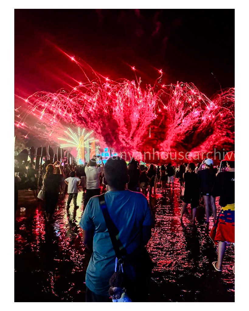 Crowd watching a brilliant red fireworks display at night