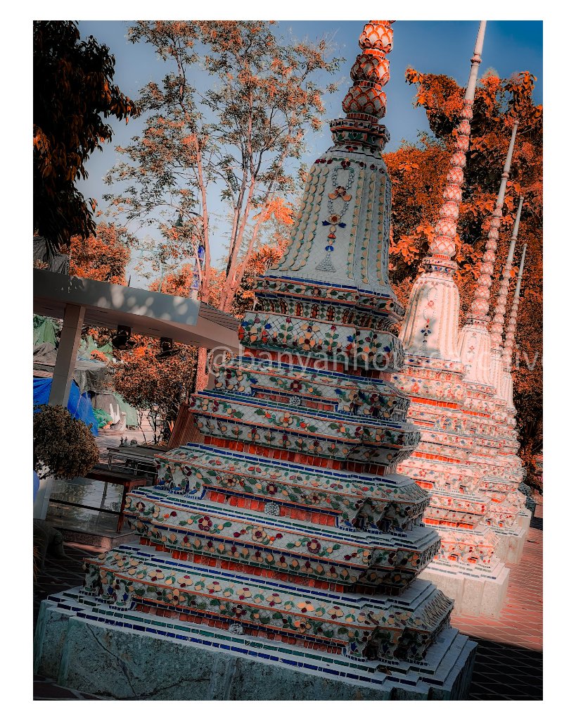Ornate mosaic-tiled Buddhist stupas against a blue sky