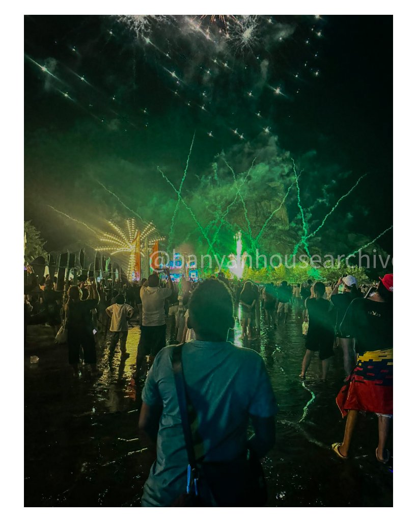 Green and white fireworks bursting over a nighttime crowd