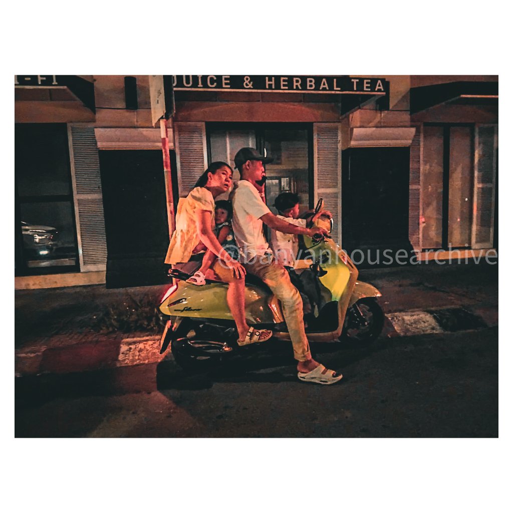 Family of four riding a lime-green scooter at night