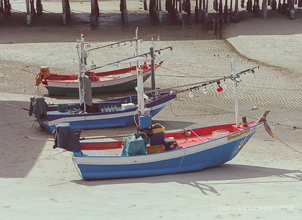 Colorful fishing boats resting on sand at low tide, Thailand