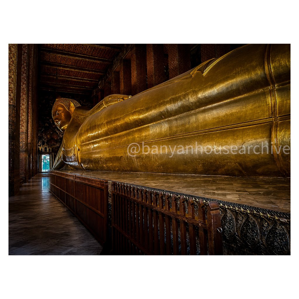 Reclining golden Buddha statue inside a dimly lit hall
