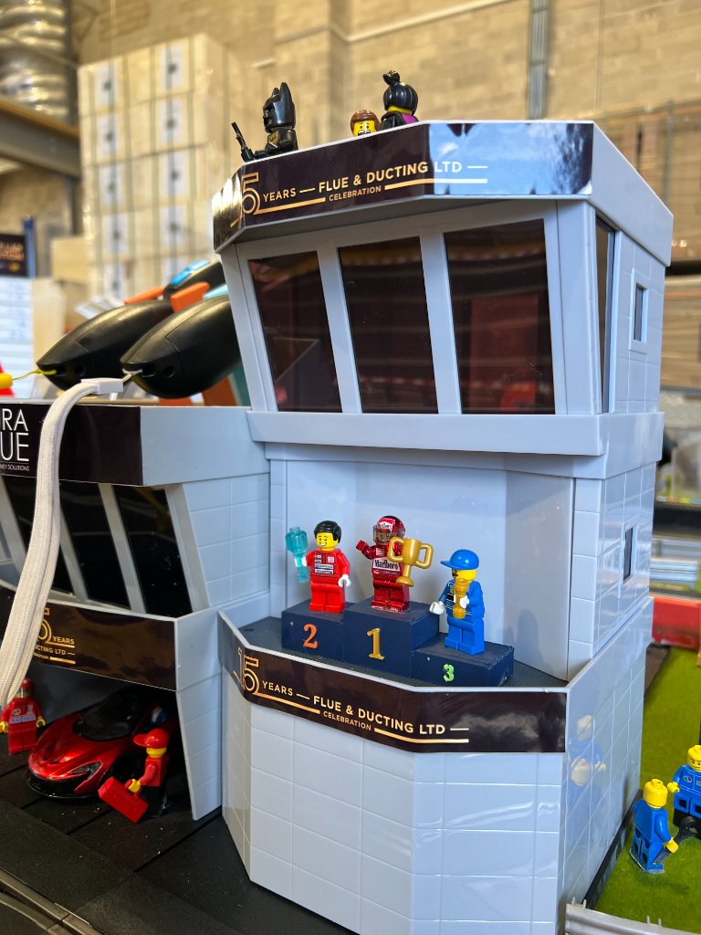 Bespoke control tower with '15 Years – Flue & Ducting Ltd' branding and podium figures