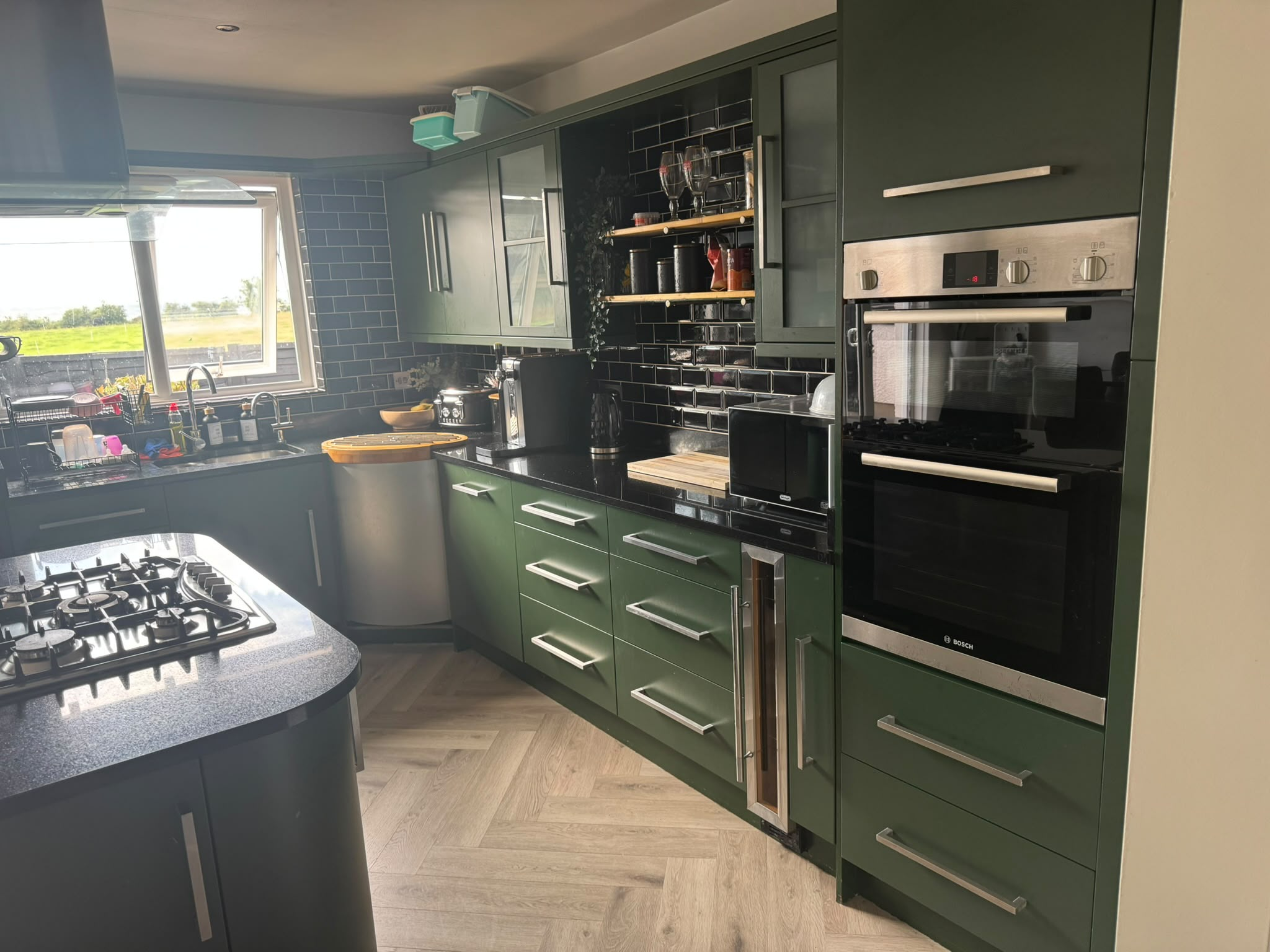 Kitchen with dark green cabinetry and black subway tiles