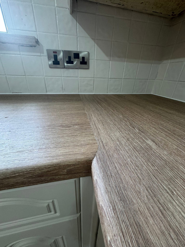 Detail of worktop joint where two dark oak vinyl sections meet
