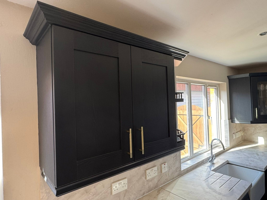 Close-up of black wood-grain wall cabinets with gold knurled handles