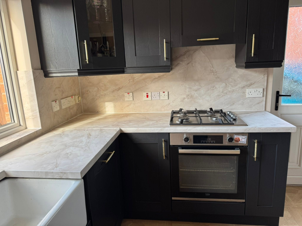 Close-up of gas hob and oven set into marble-effect wrapped worktop