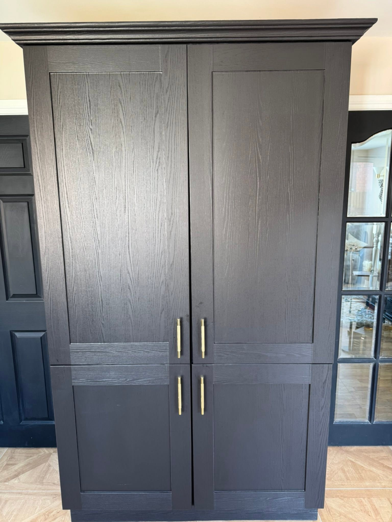 Tall floor-to-ceiling cabinet fully wrapped in black wood-effect vinyl