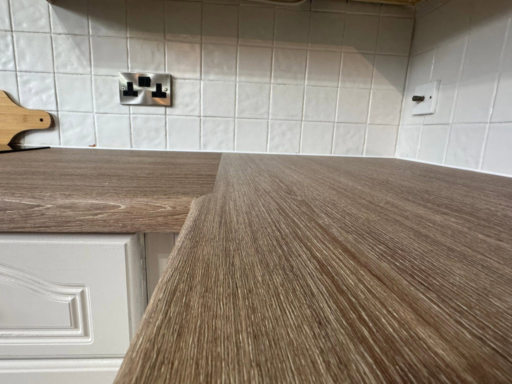Close-up of dark oak vinyl worktop corner against white tiled backsplash