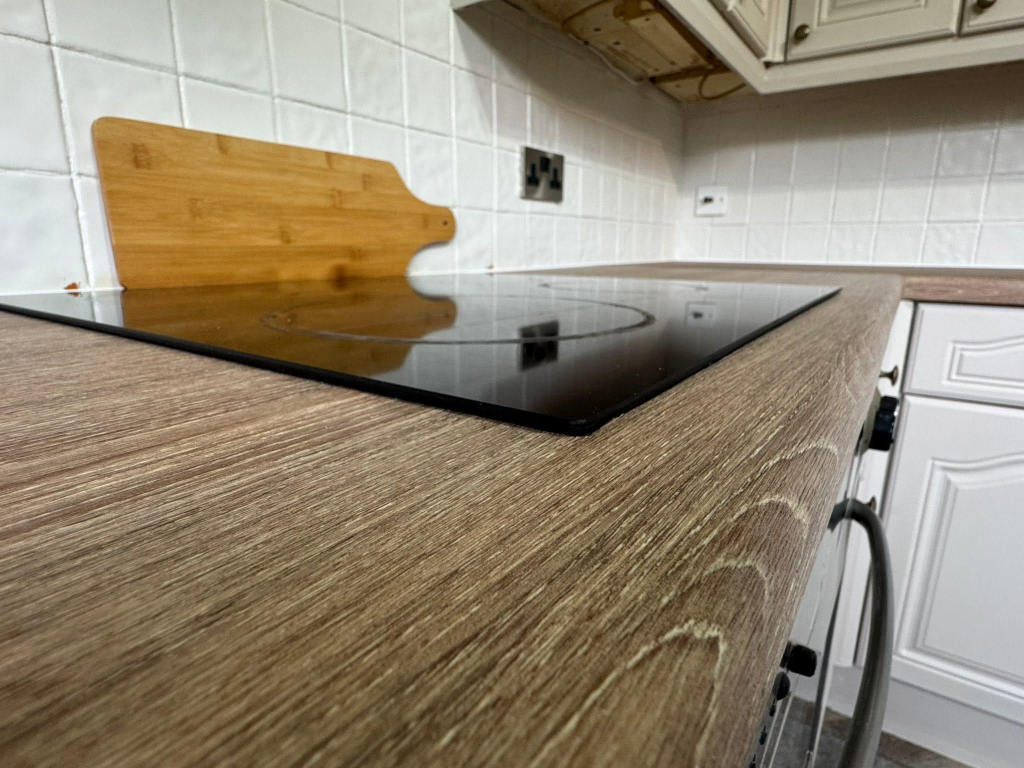 High-angle close-up of dark oak vinyl worktop with induction hob