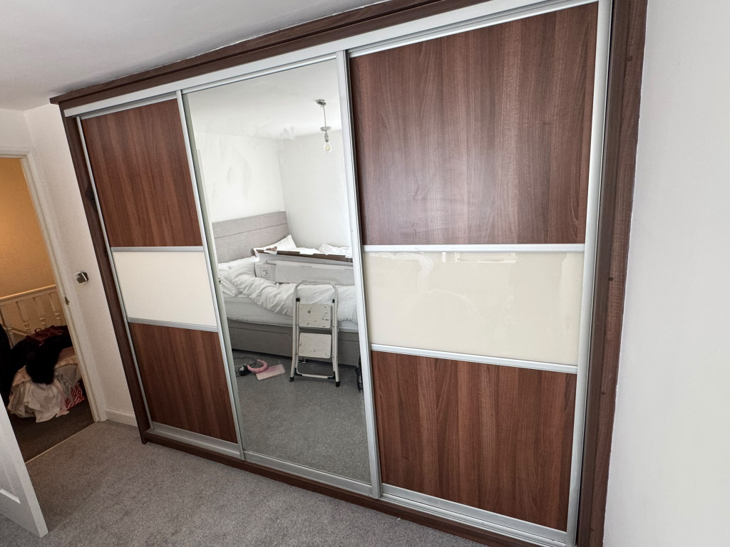 Sliding wardrobe with dark walnut and cream panels before wrap