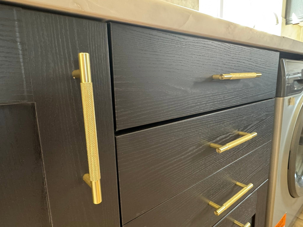 Close-up of black wood-grain drawers with gold knurled handles