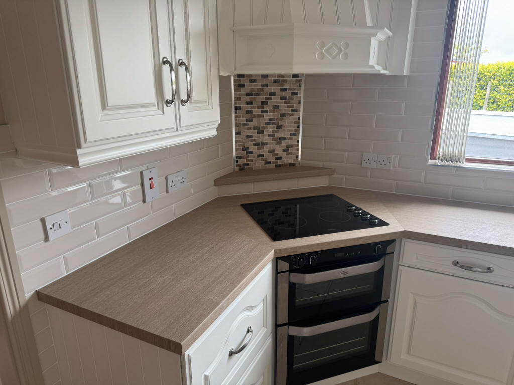 Same kitchen transformed with cream vinyl cabinets and wood-effect worktop