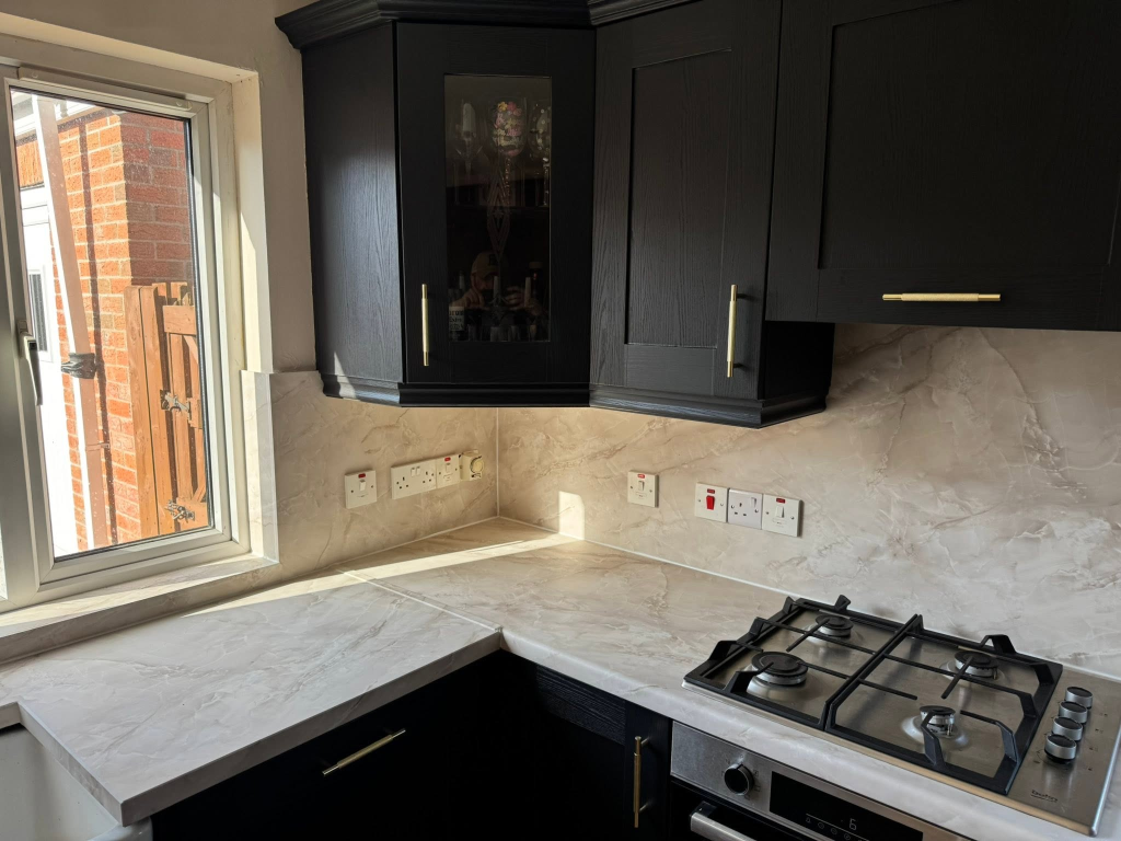 Corner of kitchen with window, glass-fronted cabinet, and marble worktop
