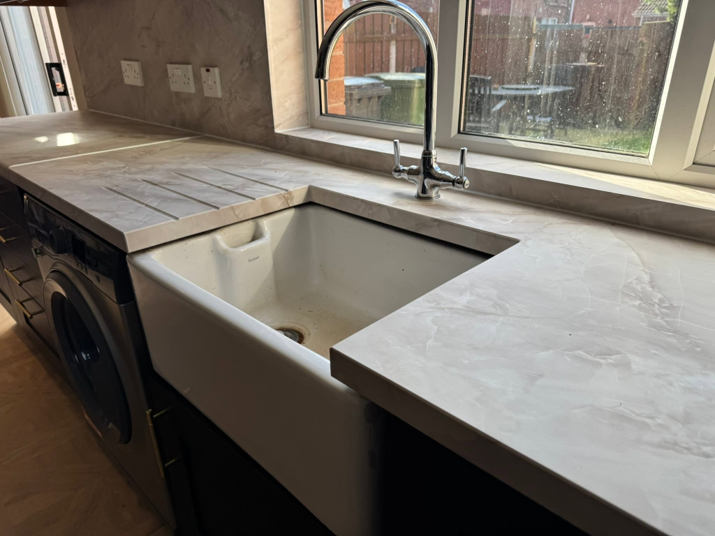 Farmhouse sink with chrome tap in marble-effect wrapped worktop