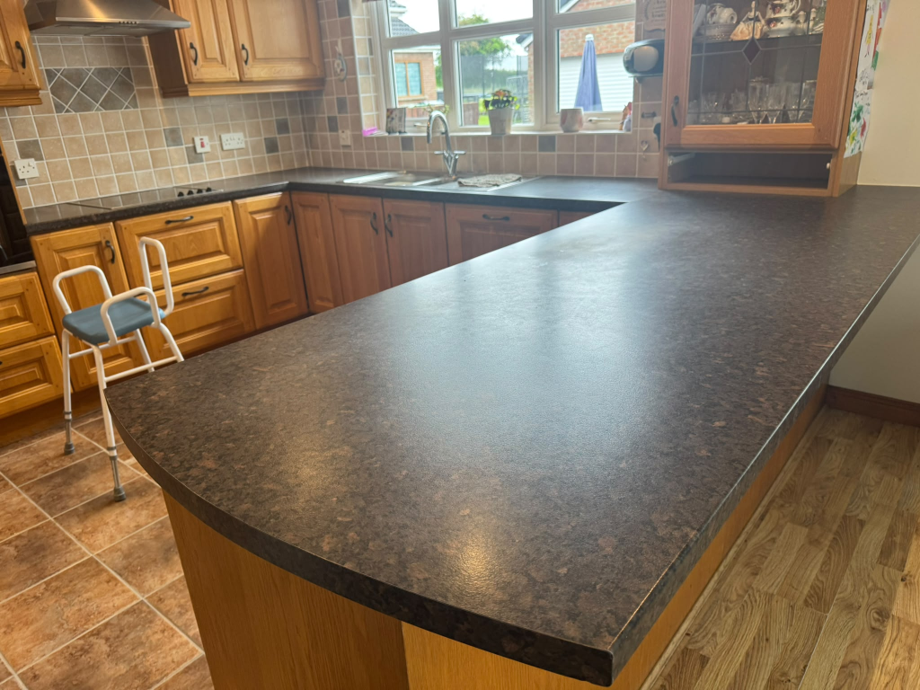 Dark speckled laminate worktop on oak cabinets in Northern Ireland before vinyl wrap
