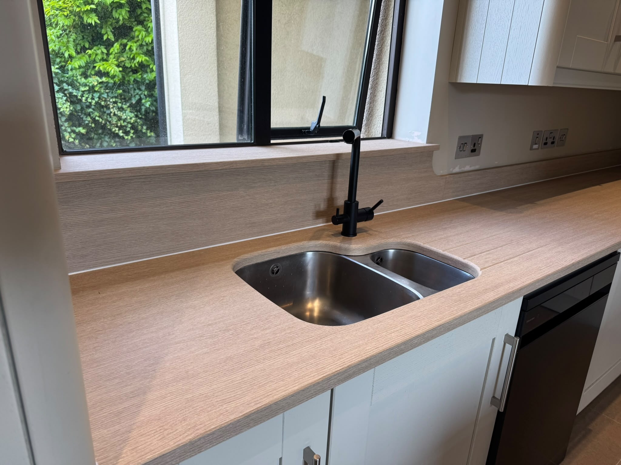 Same sink area transformed with light oak wood-effect worktop wrap