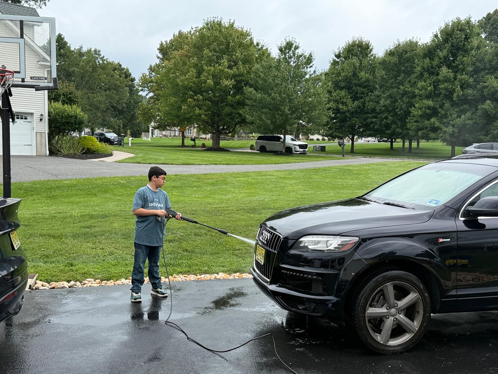 Boy pressure washing the Audi