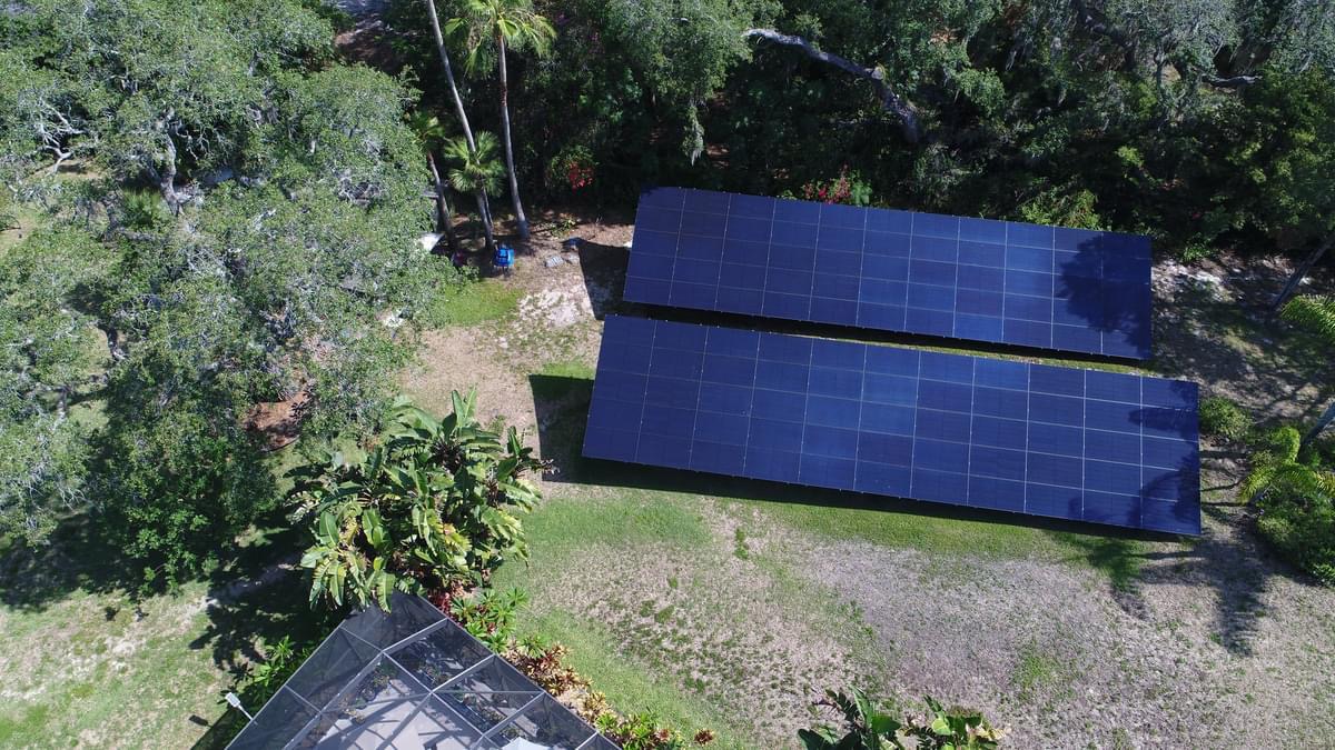 Aerial view of two ground-mounted solar arrays on a landscaped property.