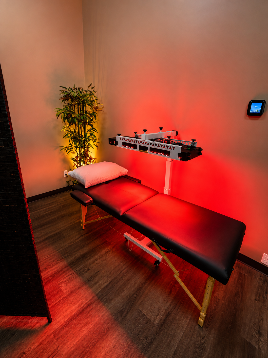 Red light therapy panel over a treatment table in a warm wellness room