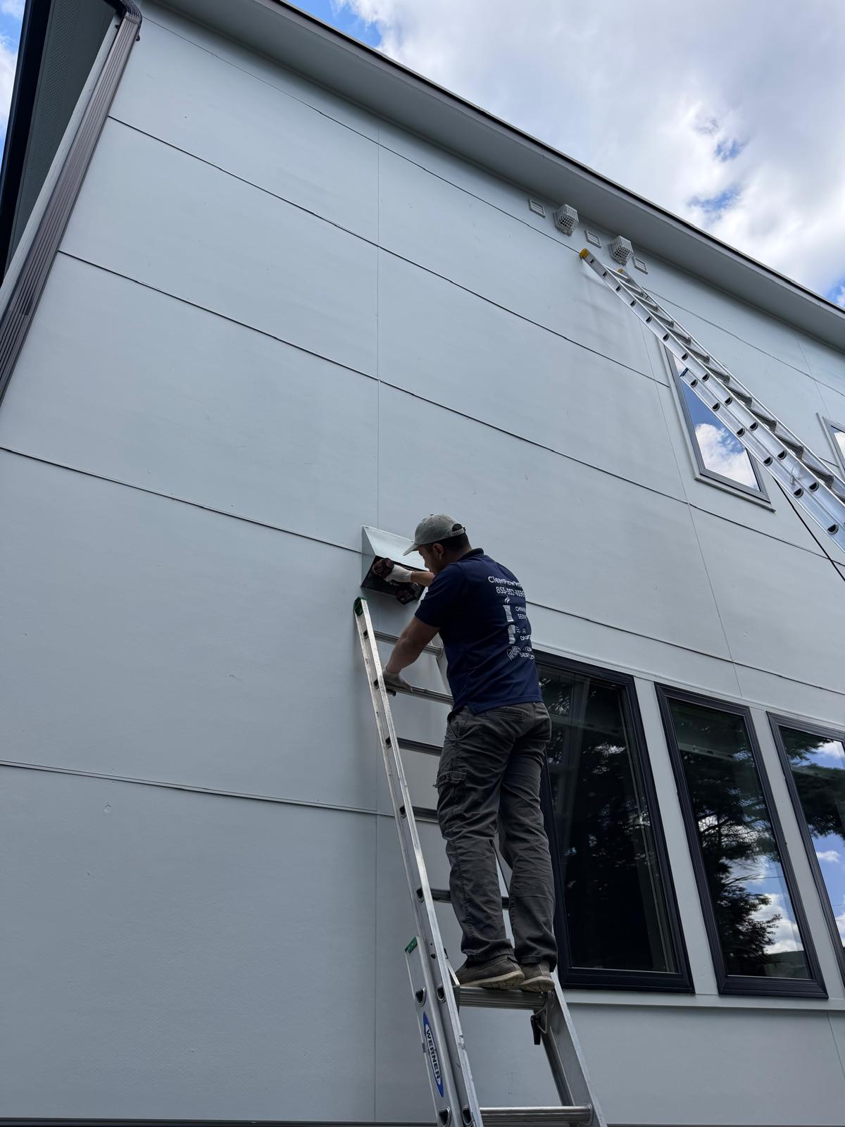 High-elevation vent bird guard installation — Northern Virginia Nova technician on extension ladder accessing roofline vent for bird guard installation