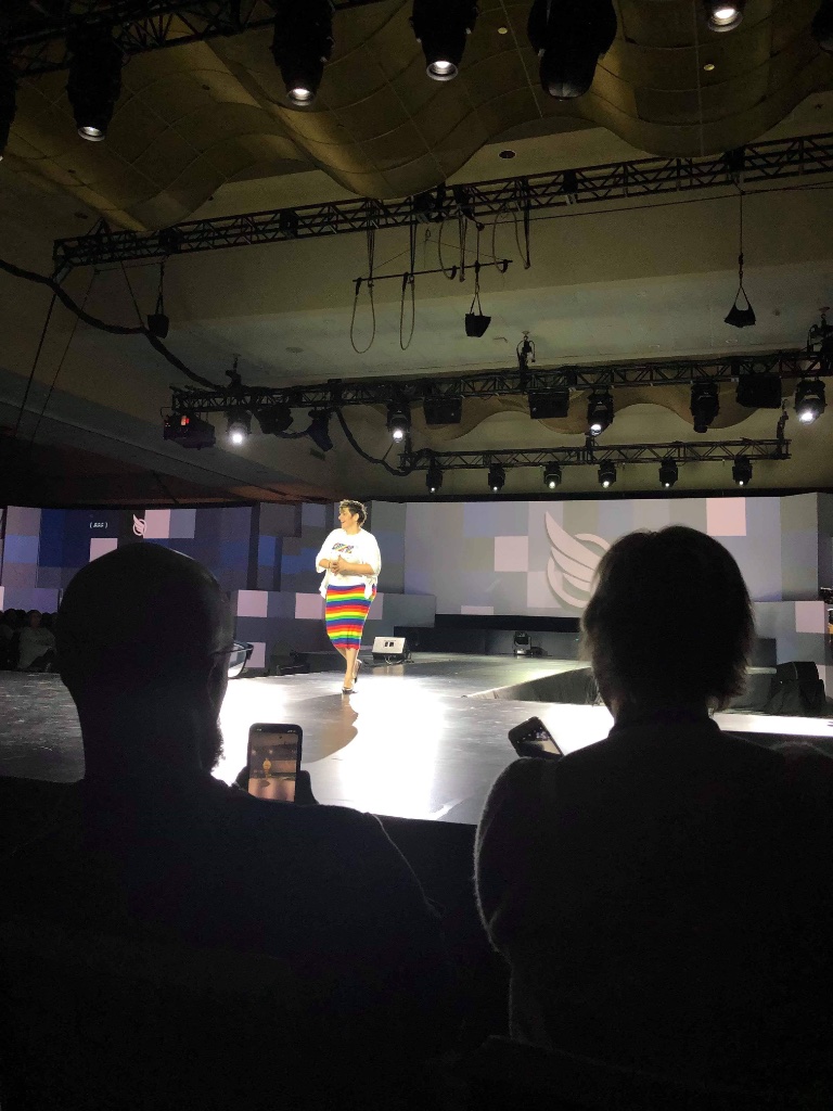 Angela on stage in rainbow skirt