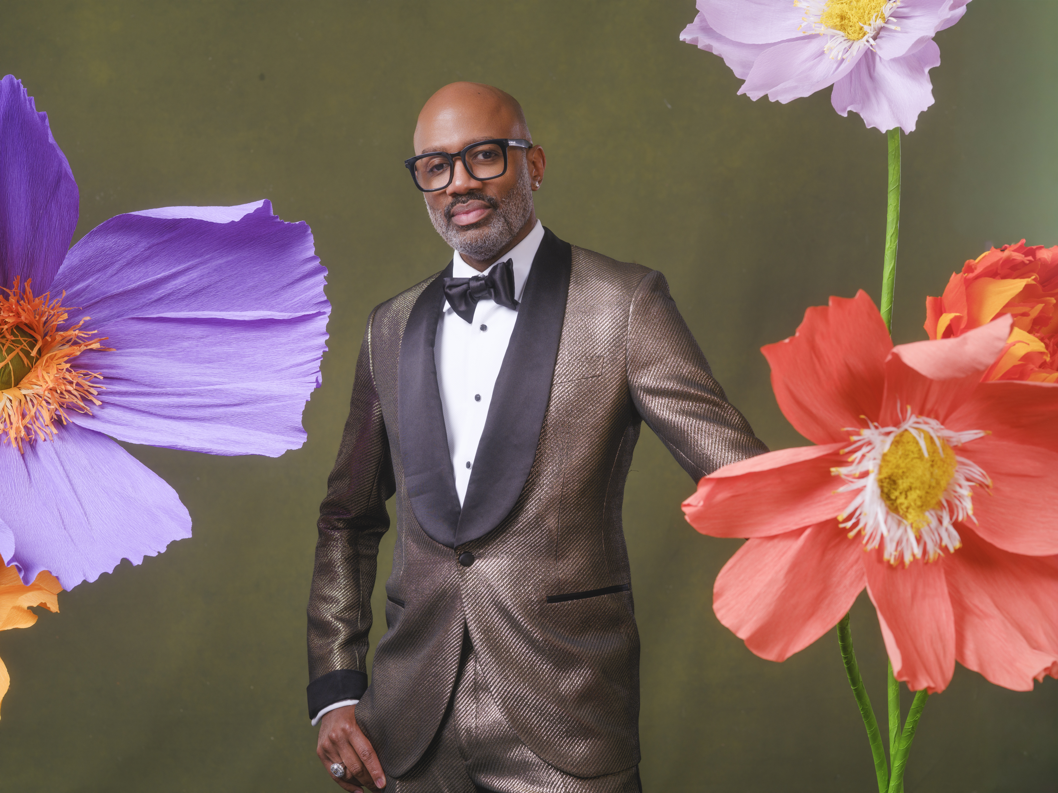 Guest in a tuxedo posed among oversized colorful flowers in a custom portrait setting