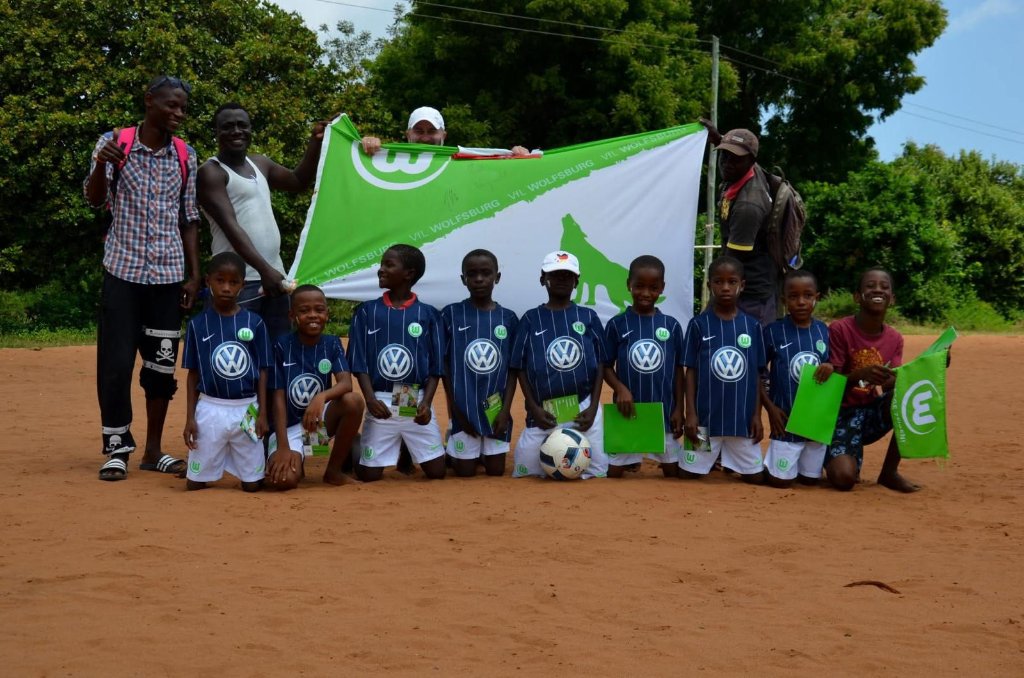 Children in VfL Wolfsburg jerseys with flag – Football IQ Academy partnership with Bundesliga