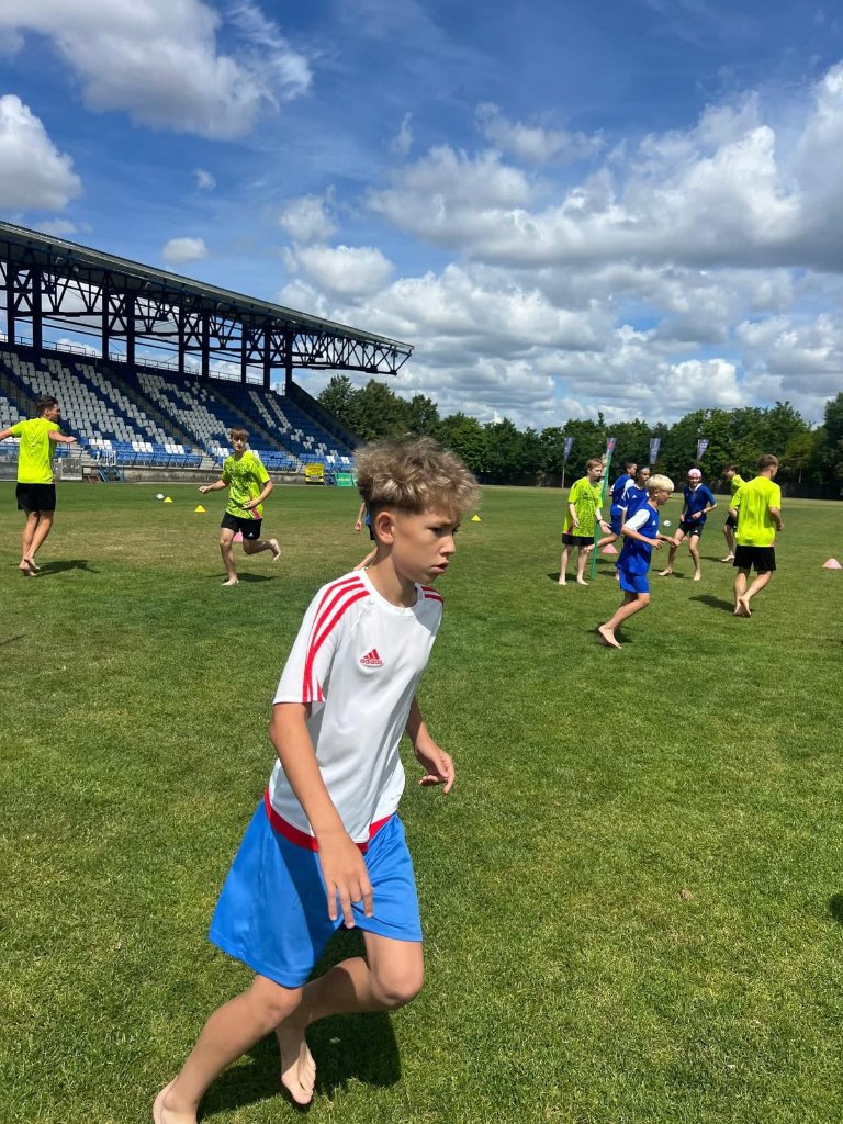 Young footballers running barefoot on stadium pitch during intensive Football IQ training