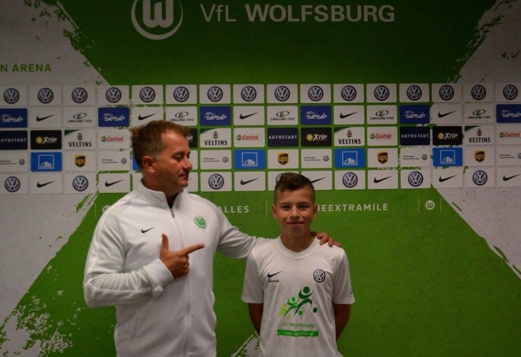 Football IQ Academy player with coach at VfL Wolfsburg press wall – camp certificate