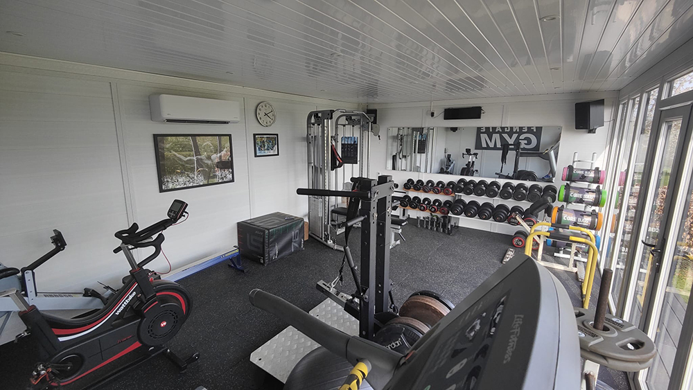 Garden gym interior with weight rack, dumbbells, and rubber flooring