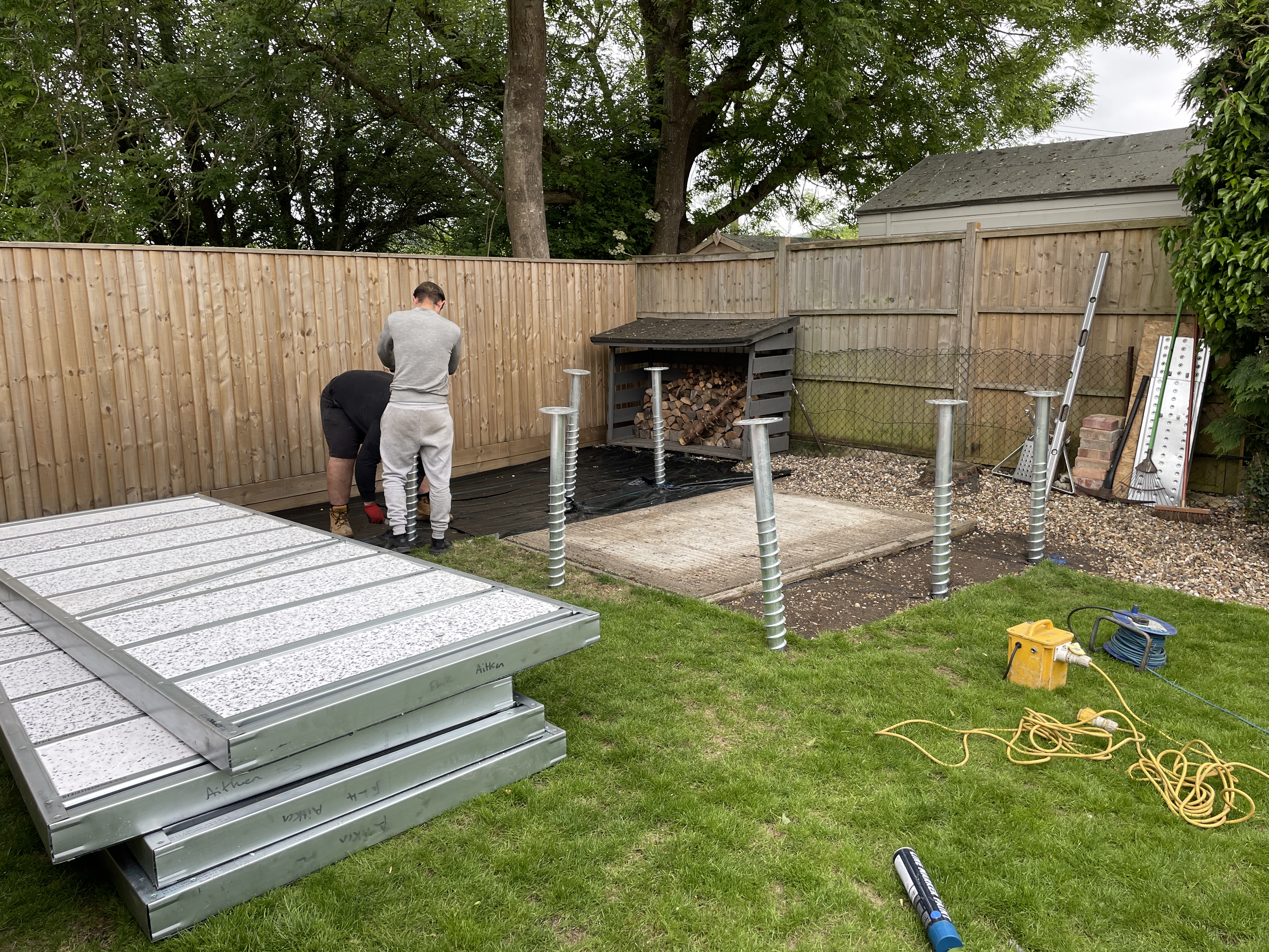 Workers installing ground screw pile foundations in a residential garden