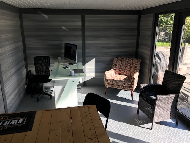 Compact garden office interior with iMac desk and accent chair