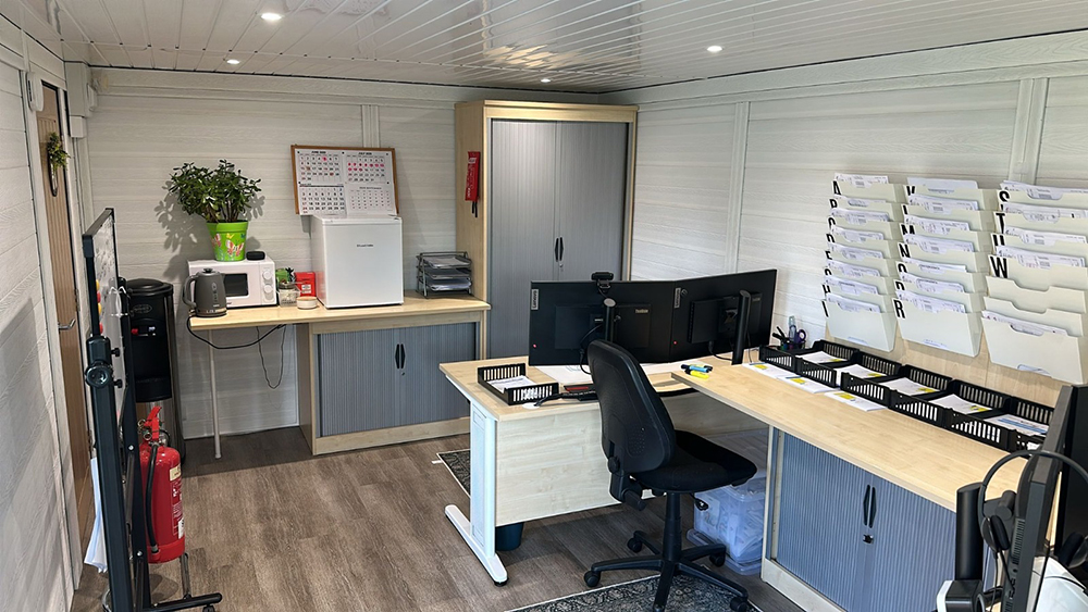 Dual workspace garden office interior with L-shaped desk and storage