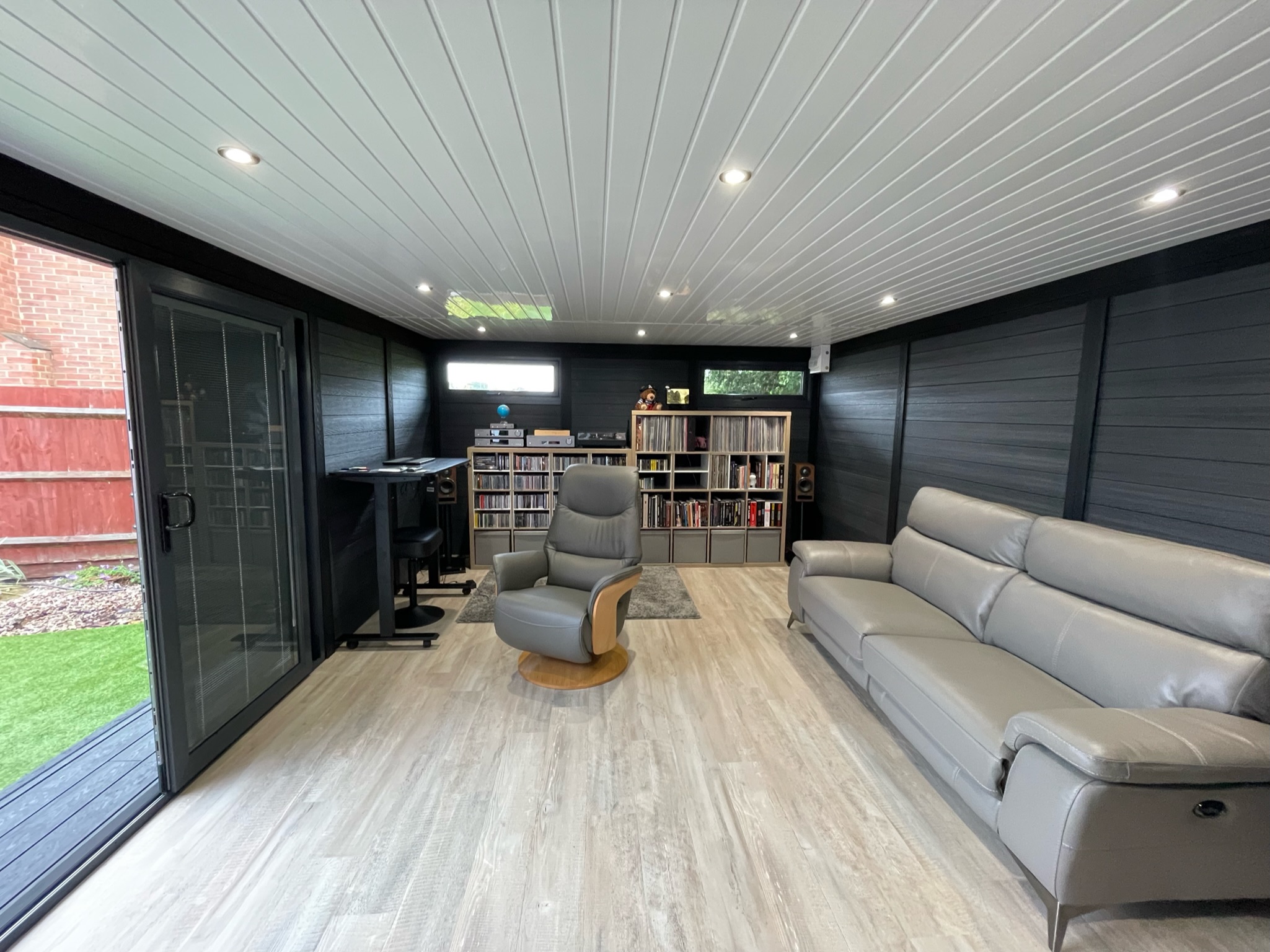 Large garden office interior with sofa, shelving and standing desk