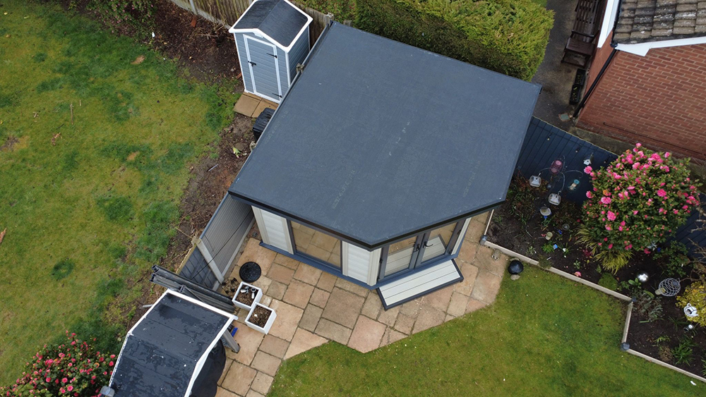Corner garden room with angled footprint and light grey cladding